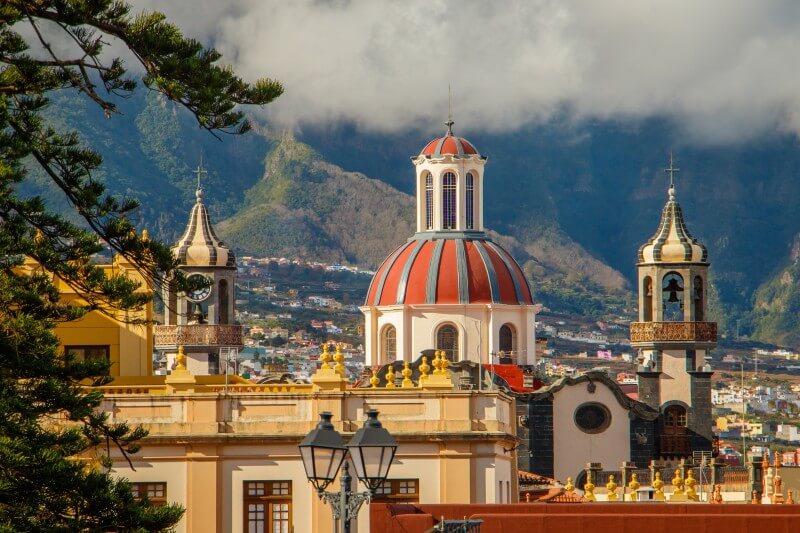 Dome and towers of the Church of the Conception in La Orotava, Tenerife, with mountain views in the background.